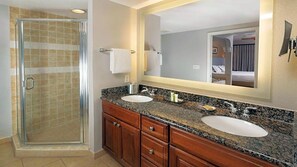 Un bagno con cabina doccia in vetro, due lavabi, uno specchio grande e mobili in legno.