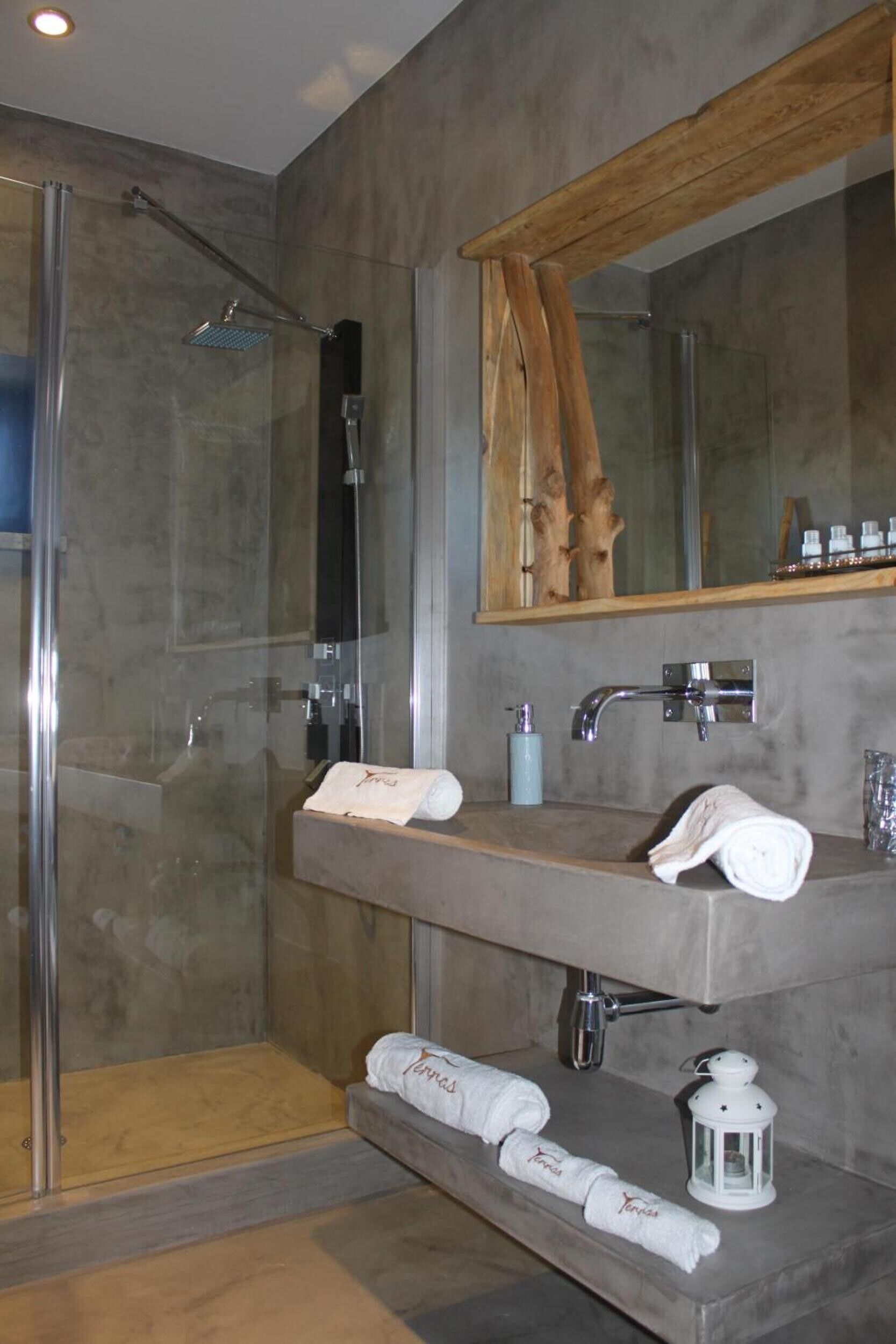 A modern bathroom with a glass shower enclosure, a wooden-framed mirror, and a vanity with a towel rack.