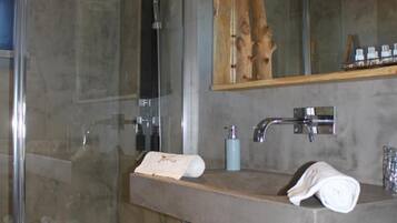 A modern bathroom with a glass shower enclosure, a wooden-framed mirror, and a vanity with a towel rack.