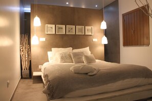 Ein Schlafzimmer mit einem großen Bett, zwei Nachttischen, einem Wandregal und einer hängenden Deckenleuchte.