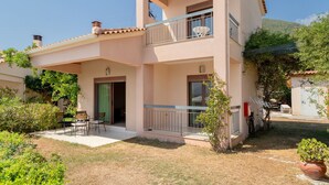 A two-story building with a balcony, a door, and a small patio area with chairs. - Villa 'Fedra' with Balcony and Air Conditioning (Marathiás)