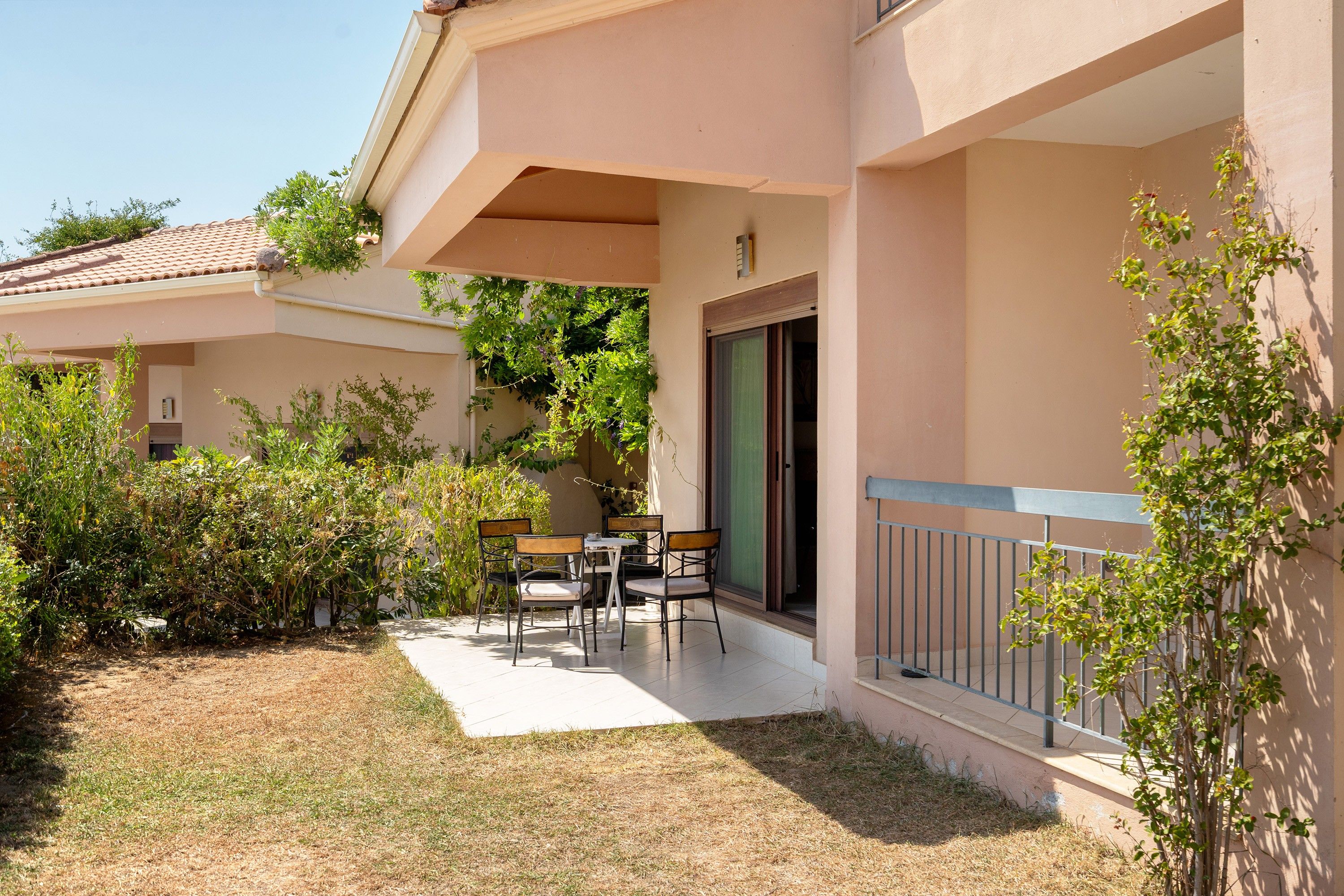 A building with a covered outdoor seating area, a door, and a small garden.