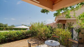 An outdoor patio with a table and chairs, surrounded by greenery and a view of the landscape. - Villa 'Fedra' with Balcony and Air Conditioning (Marathiás)