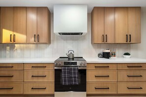 A modern kitchen with wooden cabinets, a built-in oven, and a kettle on the stove. - NEW|The Belmont @ Kierland |Updated Oasis w/Pool (Scottsdale)