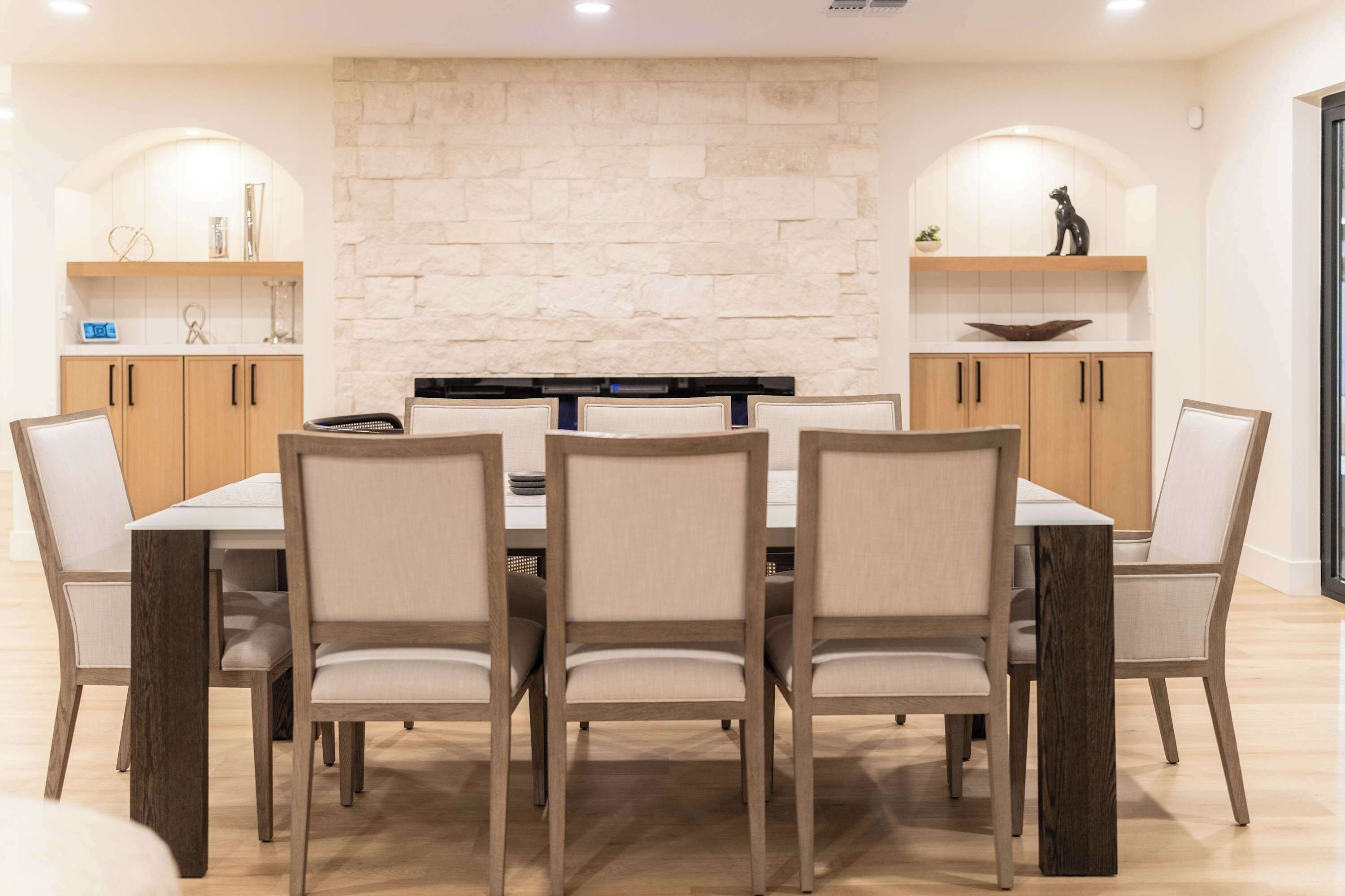 A dining area with a stone wall, wooden cabinets, and a central table with chairs.