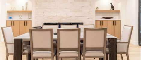 Un espace repas agrémenté d’un mur en pierre, de meubles en bois et d’une table centrale entourée de chaises.