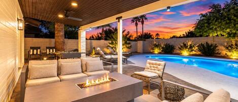 An outdoor patio with a fire pit, seating, and a pool.