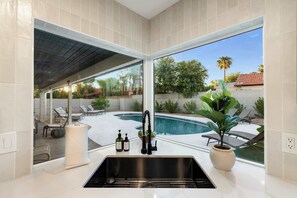 A kitchen with a large window overlooking a swimming pool and outdoor seating area. - NEW|The Belmont @ Kierland |Updated Oasis w/Pool (Scottsdale)