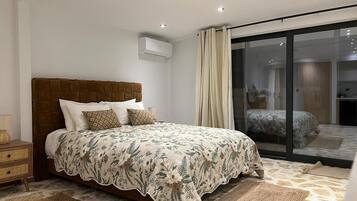 Een slaapkamer met een bed, nachtkastjes, een raam en een glazen schuifdeur naar een balkon.