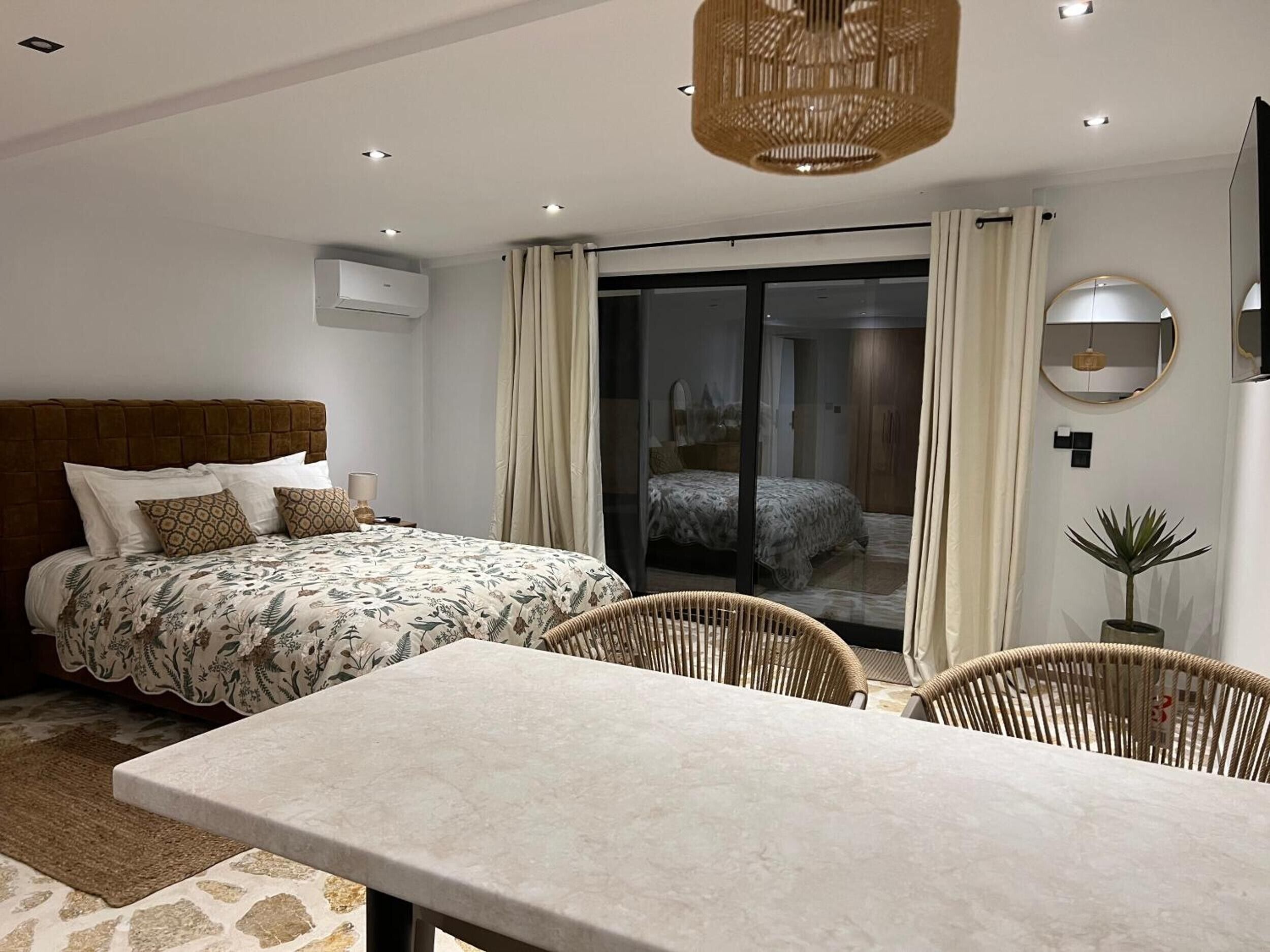 Een moderne slaapkamer met een bed, een tafel en een stoel. Er is een schuifdeur naar een balkon.