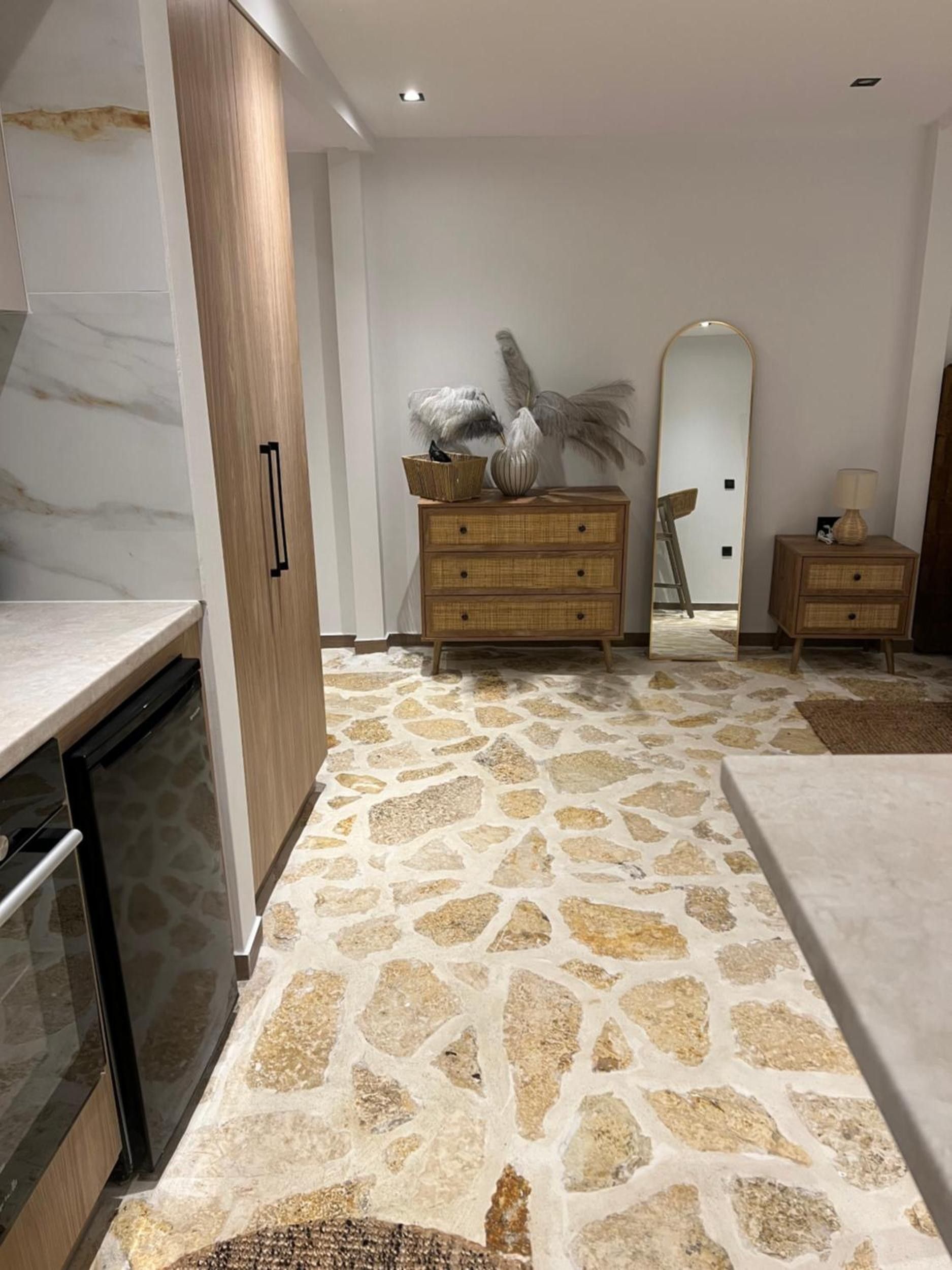 Une cuisine moderne avec un sol à motifs de pierre, des meubles en bois et un lave-vaisselle encastré.
