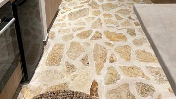 Une cuisine moderne avec un sol à motifs de pierre, des meubles en bois et un lave-vaisselle encastré.