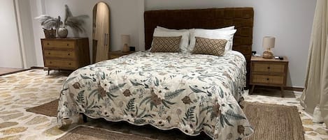 Ein Schlafzimmer mit einem großen Bett, zwei Nachttischen, einem Spiegel und einer Tür.