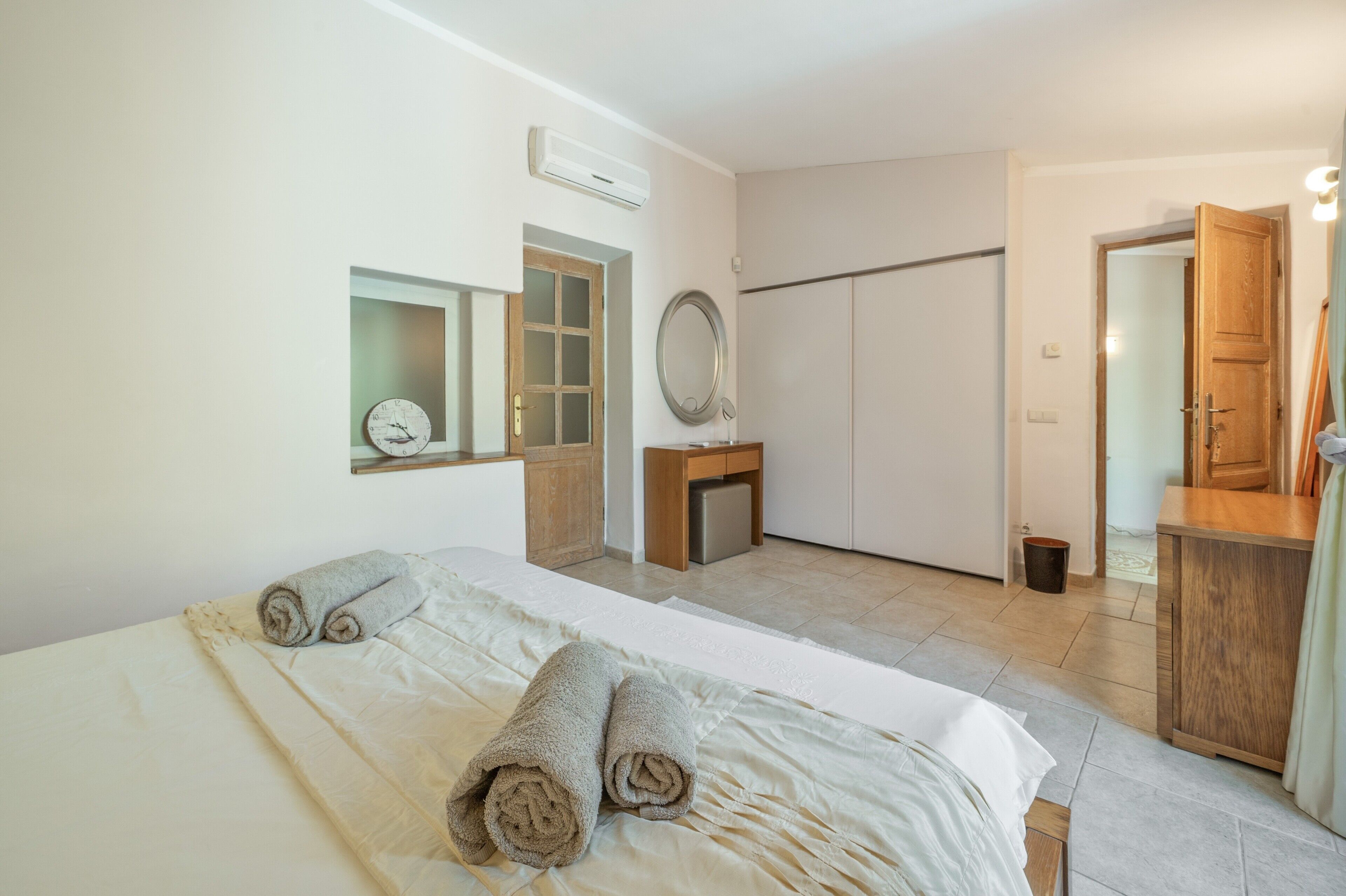 A hotel room with a bed, a wardrobe, a mirror, and a door.