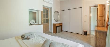 A hotel room with a bed, a wardrobe, a mirror, and a door.