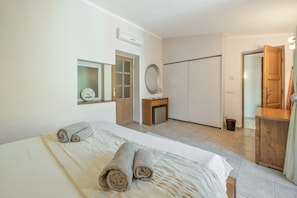 Quarto de hotel com cama, guarda-roupa, espelho e porta.