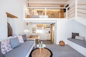 A modern loft-style living space with a loft bed, a dining area, and a kitchen.