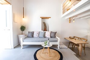 A modern living room with a white sofa, a dining table, and a small coffee table.