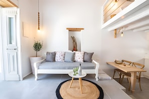 A modern living room with a sofa, a coffee table, a dining table, and a potted plant. - Villa 'Grannys 1' with Mountain View, Wi-Fi and Air Conditioning (Karpathos)