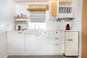 A compact kitchen with white cabinetry, a built-in oven, and a small refrigerator.
