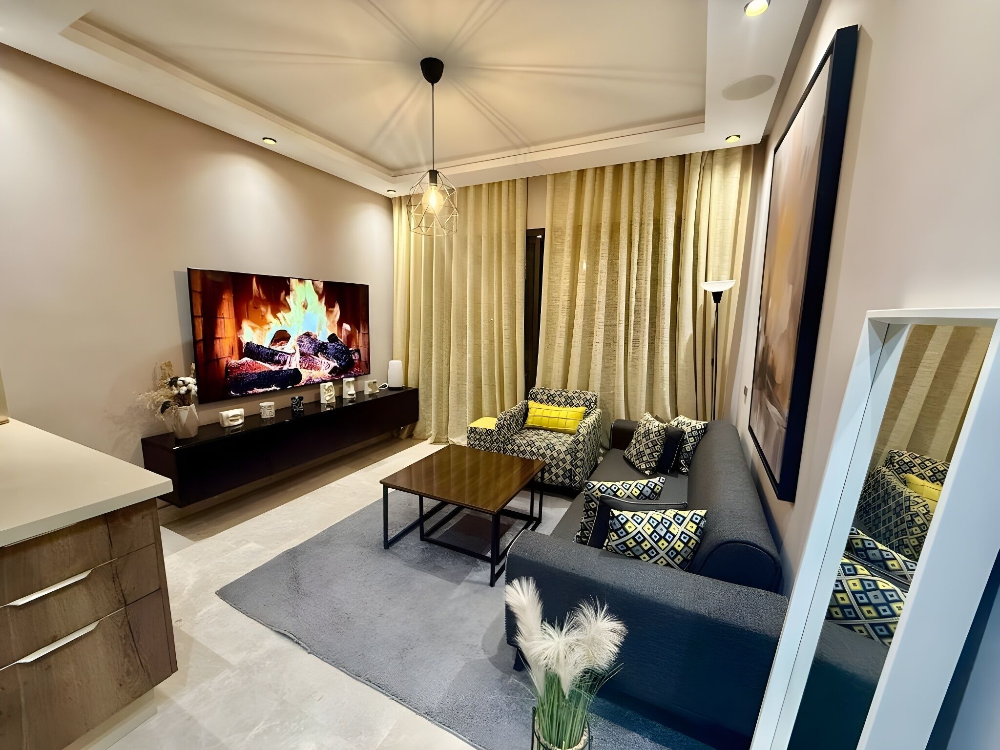 A modern living room with a flat-screen TV, sofa, coffee table, and decorative pillows.