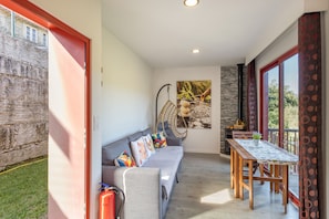 Een modern interieur met een grijze bank, een hangstoel, een eettafel en een groot raam.