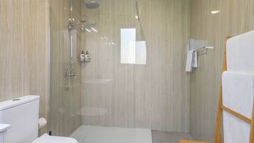 A modern bathroom with a glass-enclosed shower, a toilet, and a wooden bench.