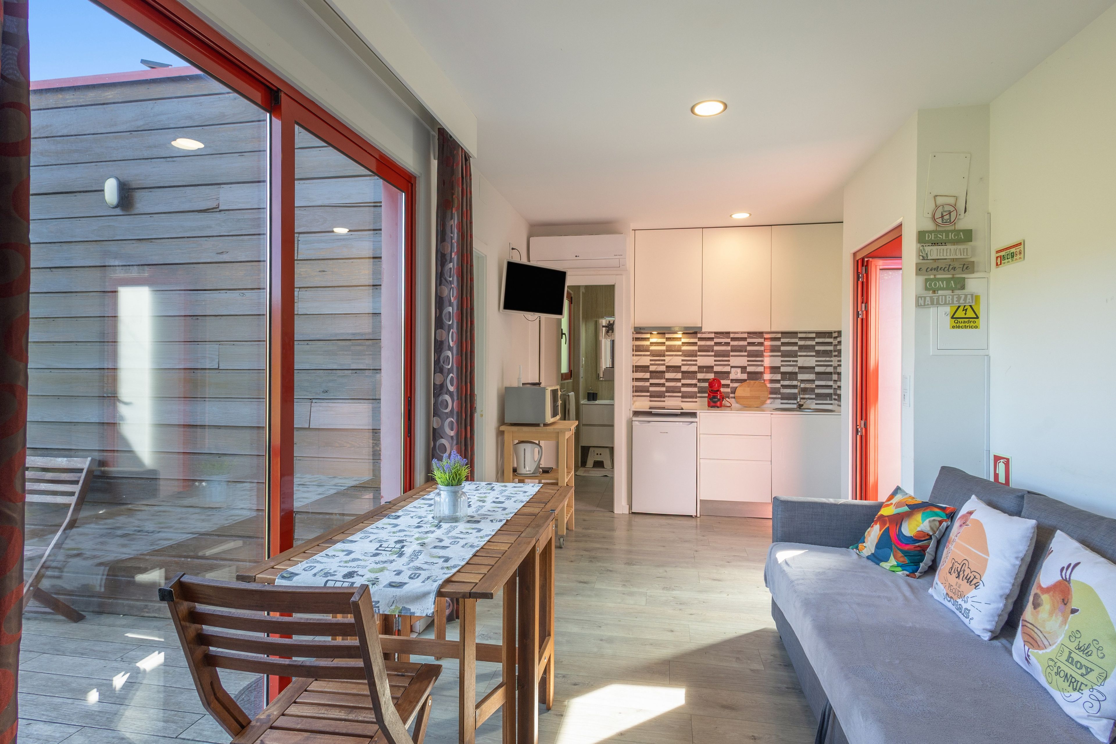 A compact living space with a dining area, kitchenette, and a sofa with colorful cushions.