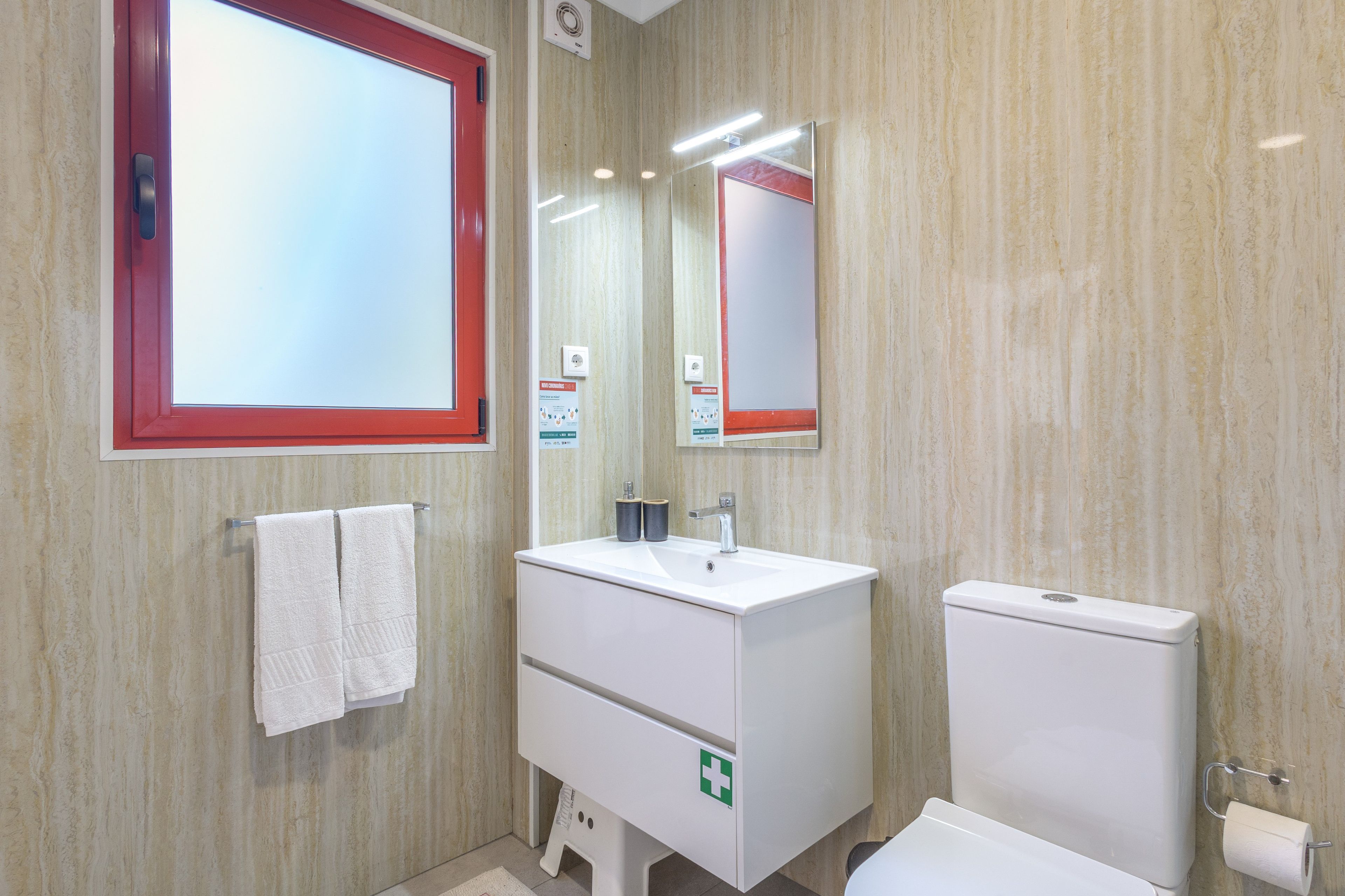 Une salle de bain avec un lavabo blanc, des toilettes et un miroir.