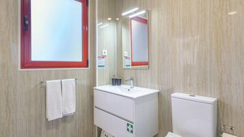 Une salle de bain avec un lavabo blanc, des toilettes et un miroir.