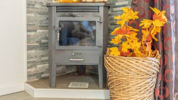 A corner room with a grey cabinet, a wicker basket with autumn leaves, and a patterned curtain.