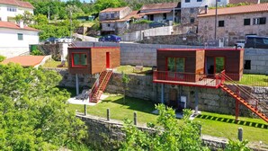 Two wooden cabins with red railings and a staircase, surrounded by greenery and stone walls. - Bungalow 'Casinhas Do Minho' with Lake View, Wi-Fi and Air Conditioning (Ázere)