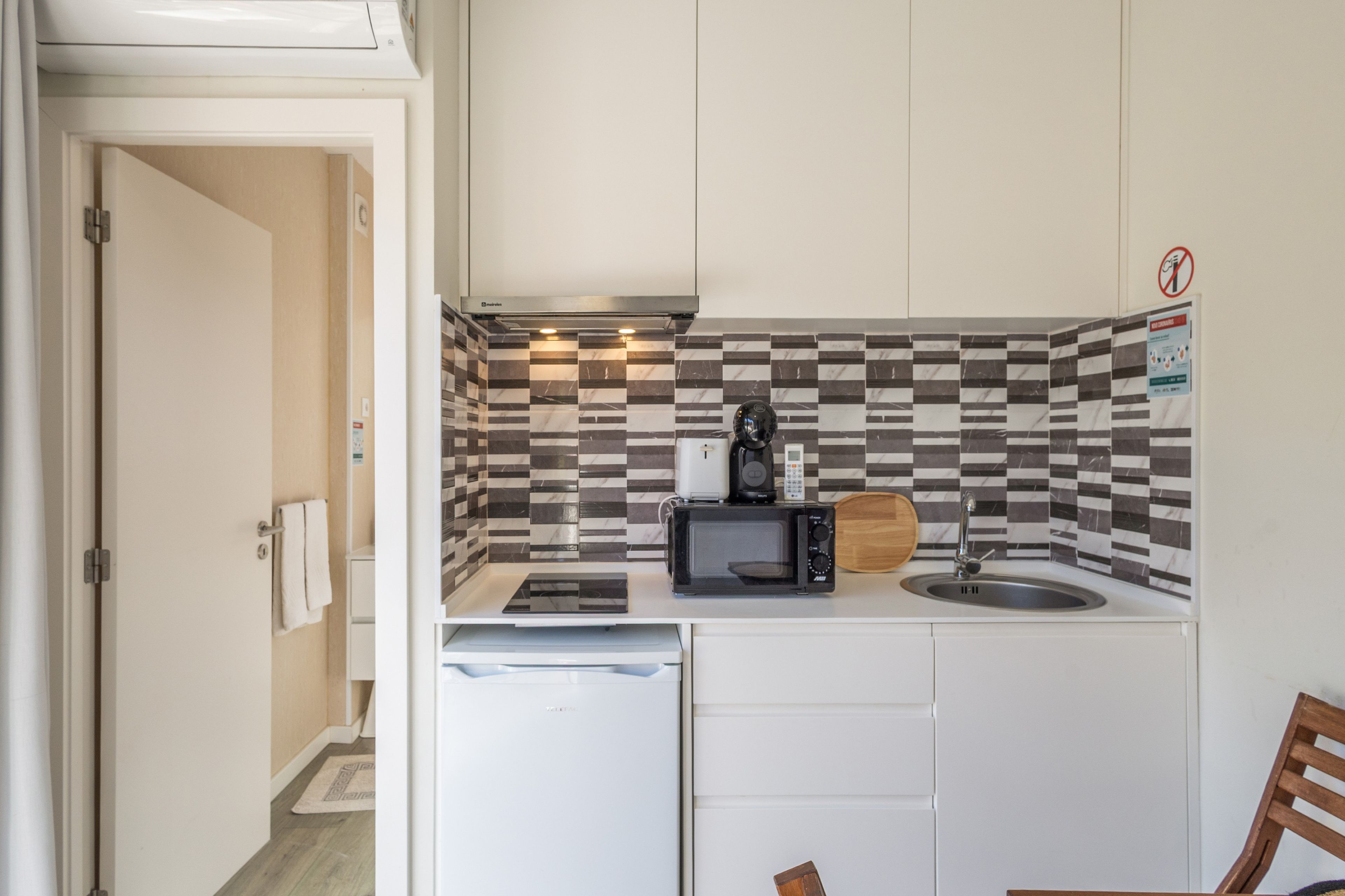A compact kitchenette with a microwave, coffee maker, and a small sink.
