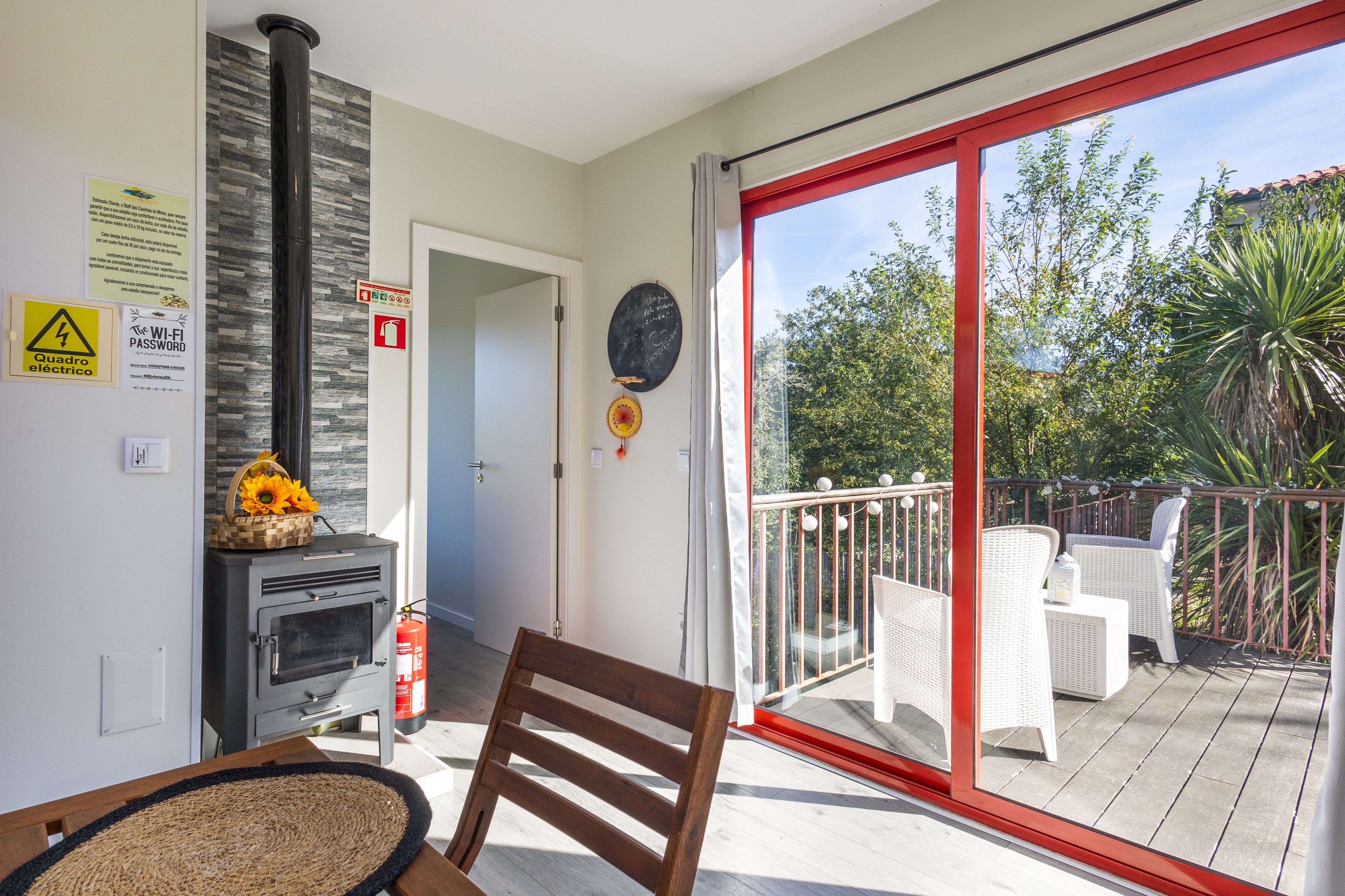 Un balcon donnant sur un espace verdoyant, une cheminée et un fauteuil.