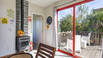 Un balcon donnant sur un espace verdoyant, une cheminée et un fauteuil.