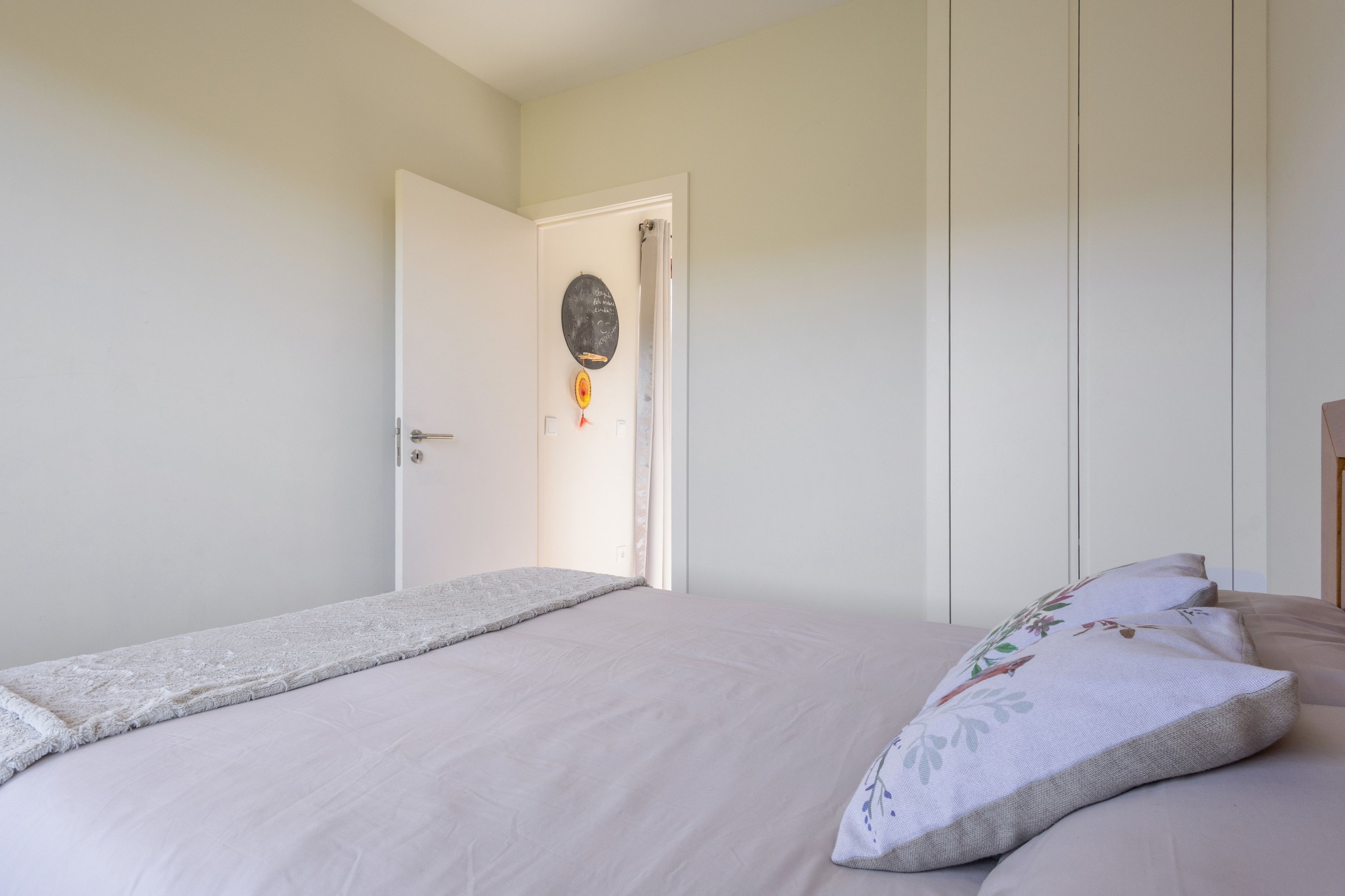A bedroom with a bed, a door, and a wall-mounted decoration.