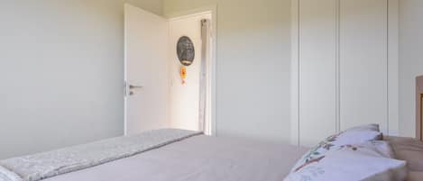 Un dormitorio con cama, una puerta y un adorno en la pared.