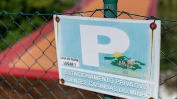 A sign with a large 'P' indicating parking, a location marker 'CASA DE PEDRA LUGAR 1', and a private parking area for 'ESTACIONAMENTO PRIVATIVO' for 'CLIENTES CASINHAS DO MINHO'.