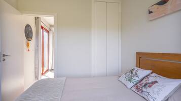 Un dormitorio con cama, almohadas, una puerta y una pared con un cuadro.
