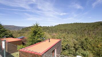 A fenced property with a red-roofed building, a satellite dish, and a view of a forested hillside.
