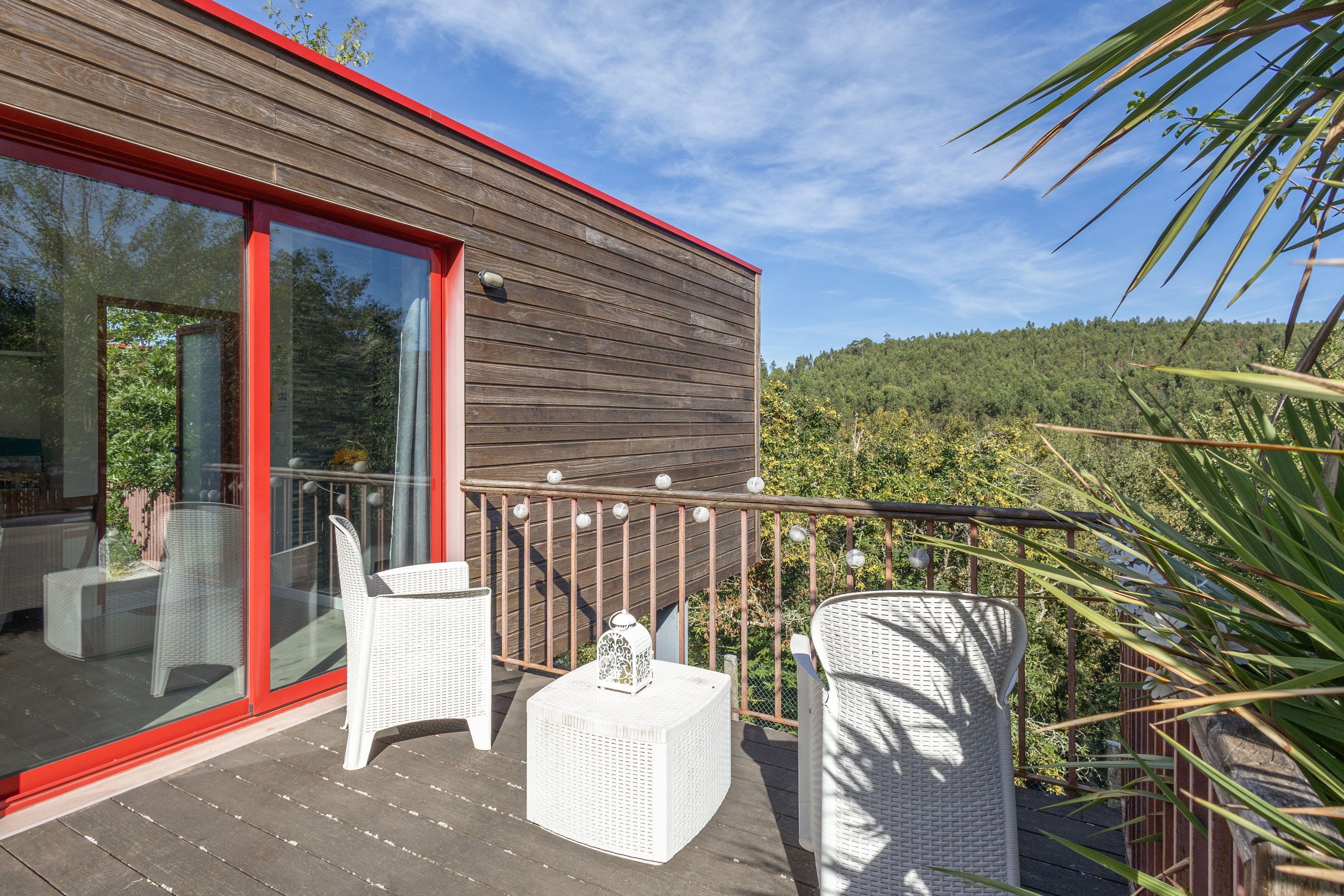 A wooden deck with wicker furniture and a glass door leading to an outdoor area.