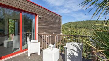 A wooden deck with wicker furniture and a glass door leading to an outdoor area.