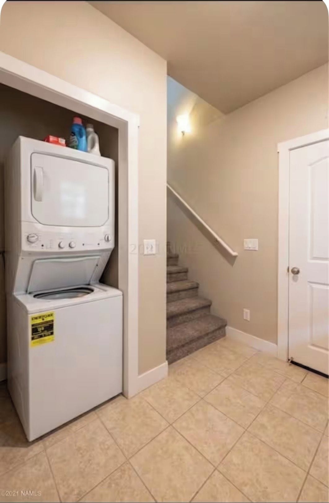 A laundry room with a washer and dryer, a staircase, and a door.