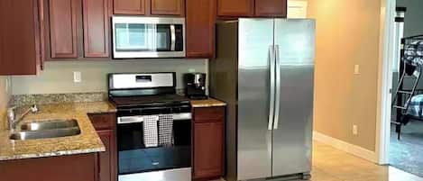 A modern kitchen with wooden cabinets, stainless steel appliances, and a granite countertop.