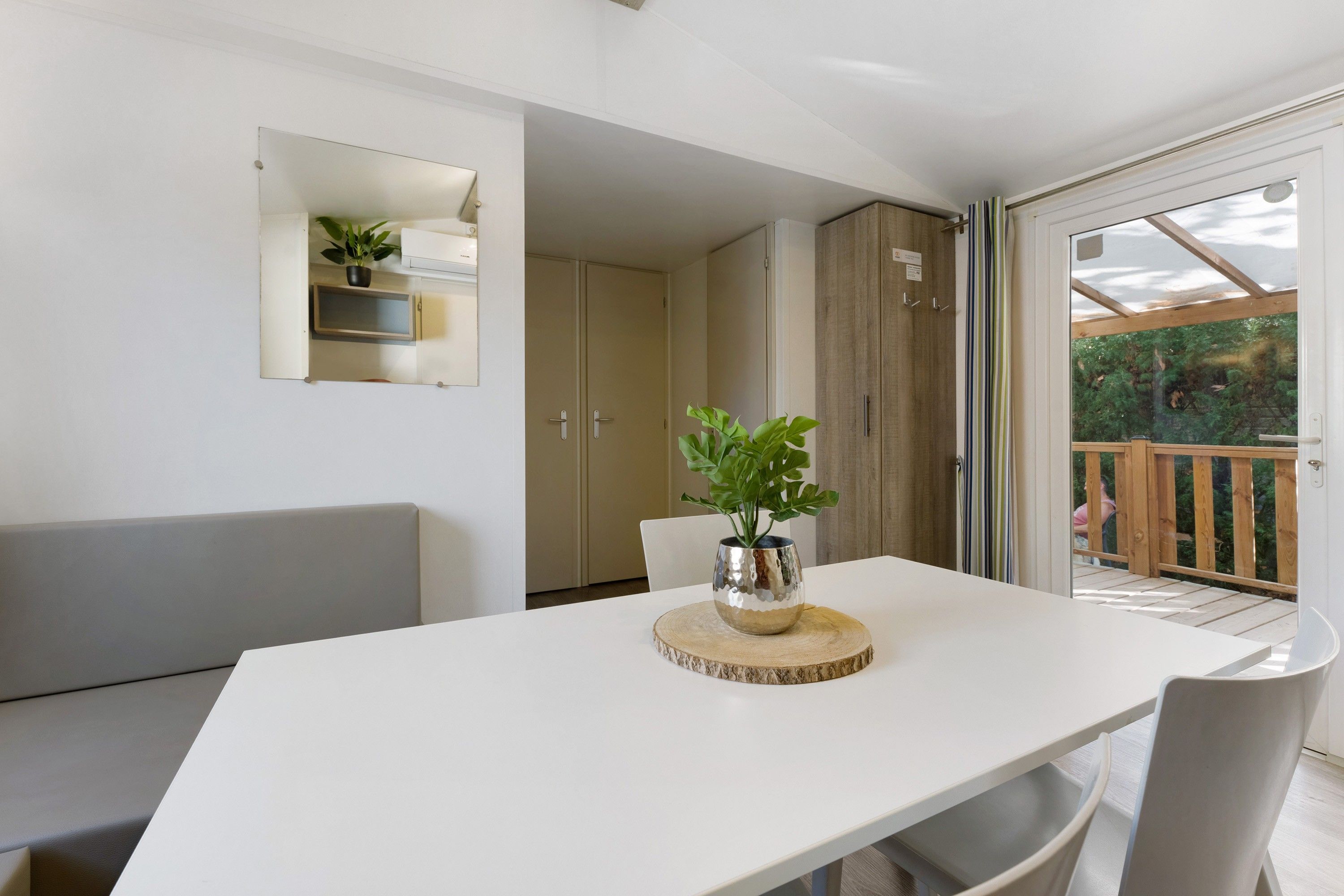 Un comedor moderno con una mesa blanca, sillas grises y una planta en maceta.