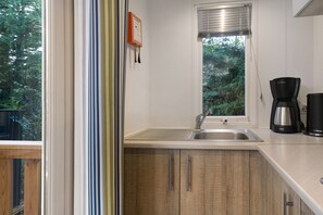 Eine Küche mit integriertem Spülbecken, einem Fenster mit Jalousien und einer Kaffeemaschine auf der Arbeitsplatte.