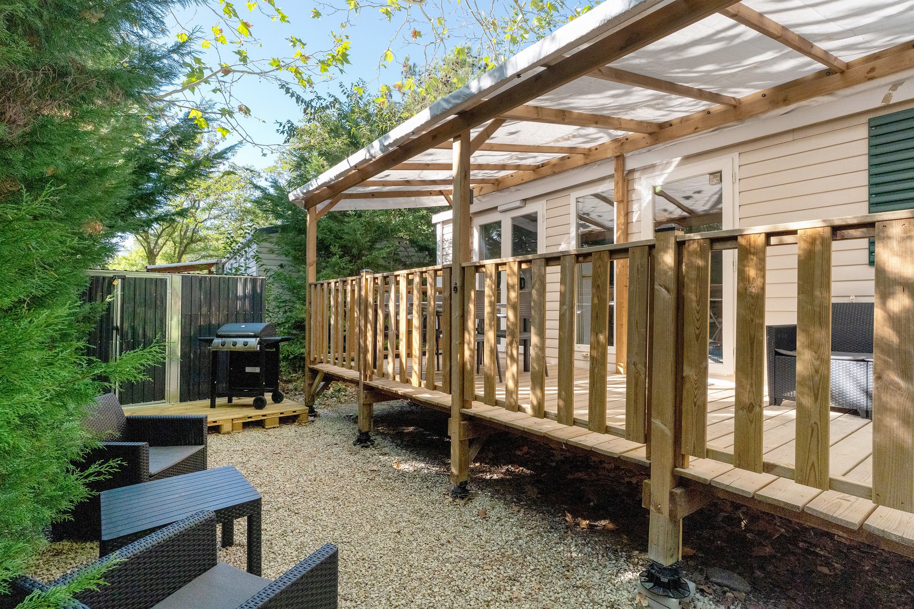A covered outdoor deck with a grill and seating area.