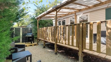 A covered outdoor deck with a grill and seating area.