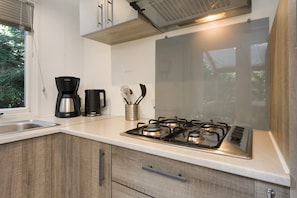 Eine moderne Küche mit Gasherd, Kaffeemaschine und einem Fenster mit Jalousien.
