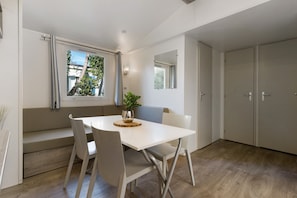 Ein moderner Essbereich mit einem weißen Tisch und Stühlen, einer Bank und einem Fenster mit Vorhängen.